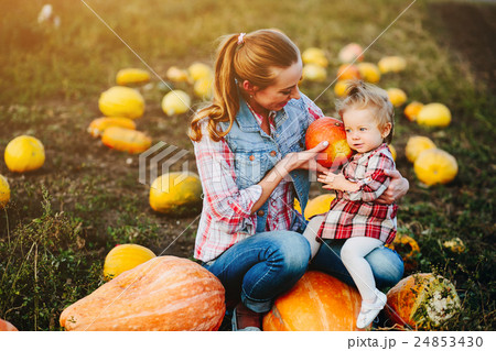Mother and daughter sitting on pumpkins 24853430