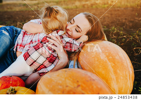 mother and daughter lie between pumpkins 24853438