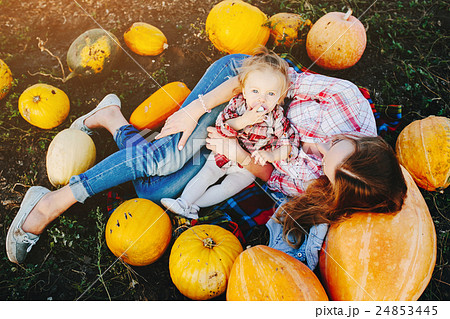 mother and daughter lie between pumpkins 24853445