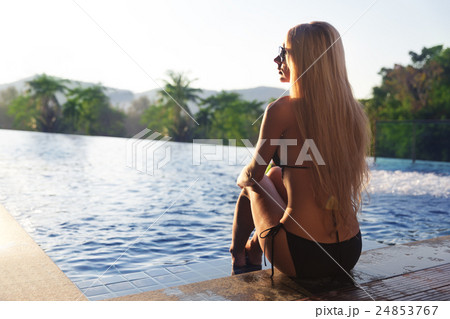 Pretty slim blonde woman gets suntan near swimming pool 24853767