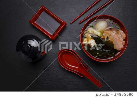 Japanese miso soup in a red bowl on the table. 24855690