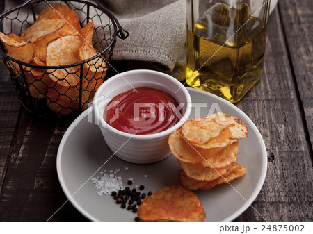 Potato crisps with ketchup on plate and olive oil 24875002