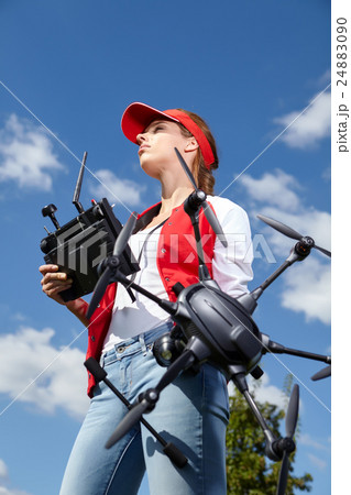 A woman is standing and holding drone over sky 24883090