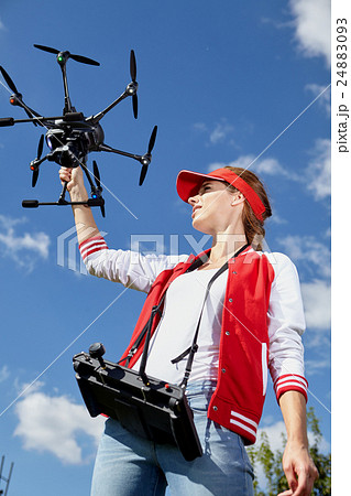 A woman is standing and holding drone over sky 24883093