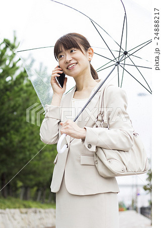 傘をさしながらスマホで会話をするビジネスウーマン 傘をさしながらスマホで会話をするビジネスウーマン 24888217