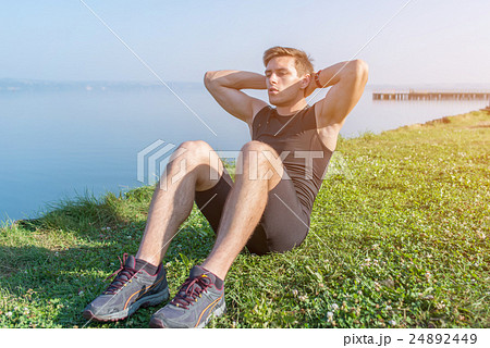 Sporty young man doing sit-ups abs crunches in 24892449