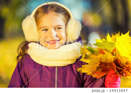 Happy little girl in earflaps with autumn leaves 24911647