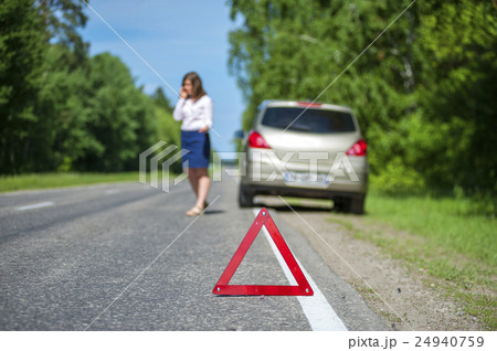 Red triangle warning sign and woman near car Red triangle warning sign and woman near car 24940759