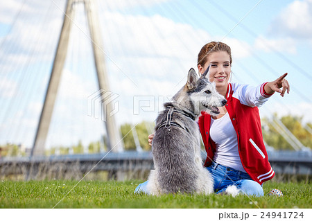 Woman playing with her dog on a city lawn 24941724
