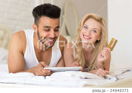 Young Couple Lying In Bed Using Tablet Computer 24948371