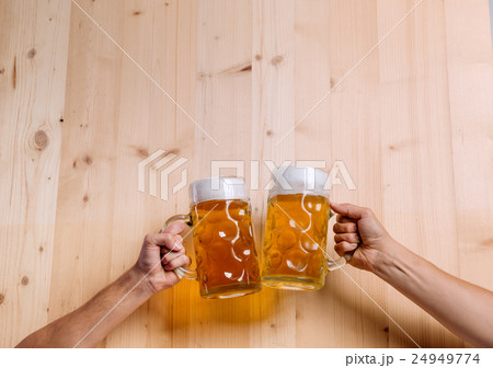 Two unrecognizable men clinking with beer mugs Two unrecognizable men clinking with beer mugs 24949774