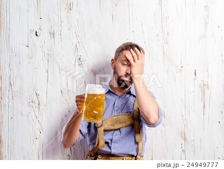 Drunk man in traditional bavarian clothes holding Drunk man in traditional bavarian clothes holding 24949777