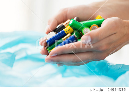 close up of hands putting batteries to rubbish bag close up of hands putting batteries to rubbish bag 24954336