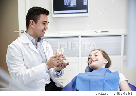 happy dentist showing jaw layout to patient girl 24954561