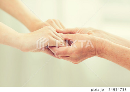 close up of senior and young woman holding hands 24954753