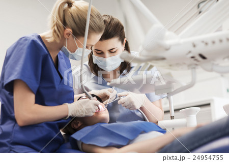 female dentists treating patient girl teeth 24954755