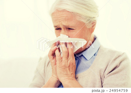 sick senior woman blowing nose to paper napkin 24954759