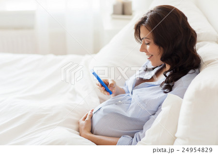 happy pregnant woman with smartphone in home bed 24954829