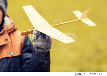 close up of little boy holding toy plane outdoors 24955170