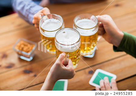 close up of hands with beer mugs at bar or pub 24955285