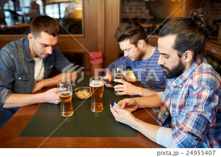 men with smartphones drinking beer at bar or pub men with smartphones drinking beer at bar or pub 24955407