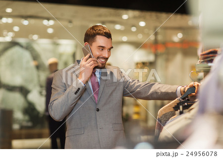 happy man calling on smartphone at clothing store happy man calling on smartphone at clothing store 24956078