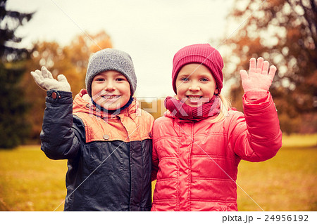 happy girl and boy waving hands in autumn park 24956192