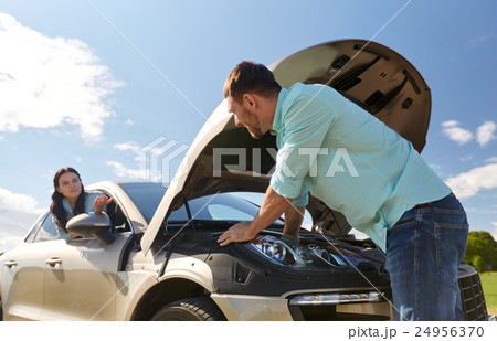 couple with open hood of broken car at countryside 24956370