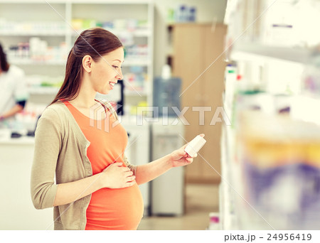 happy pregnant woman with medication at pharmacy 24956419