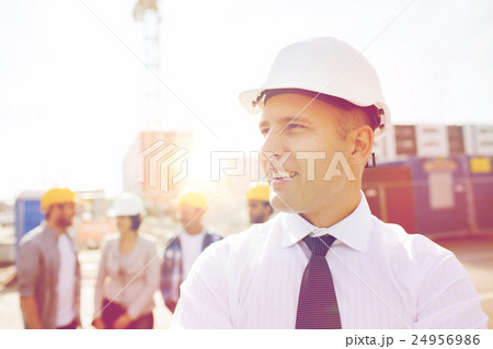 group of smiling builders in hardhats outdoors group of smiling builders in hardhats outdoors 24956986