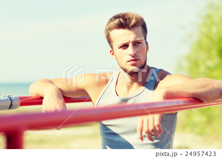 young man exercising on parallel bars outdoors 24957423
