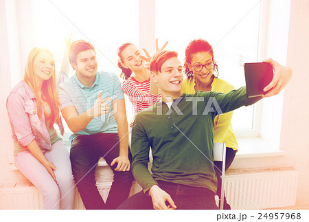 smiling students making picture with tablet pc 24957968