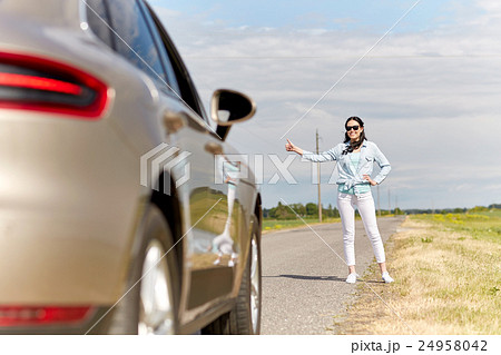woman hitchhiking and stopping car at countryside 24958042