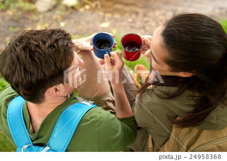 happy couple with backpacks and tea cups in nature 24958368