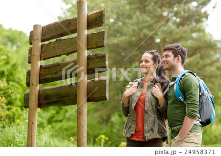 smiling couple at signpost with backpacks hiking 24958371