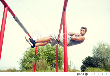 young man doing sit up on parallel bars outdoors 24958493