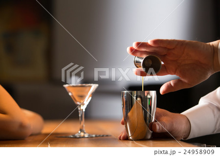 カクテルをつくるバーテンダーと女性客 24958909