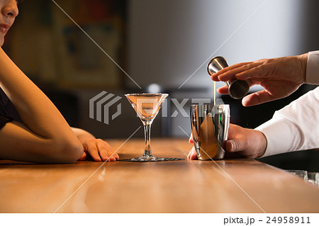 カクテルをつくるバーテンダーと女性客 24958911