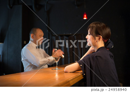 バーでシェイカーを振るバーテンと女性 24958940