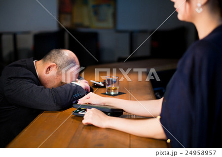 酔いつぶれたサラリーマンの財布からクレジットカードを抜き取る女性 24958957