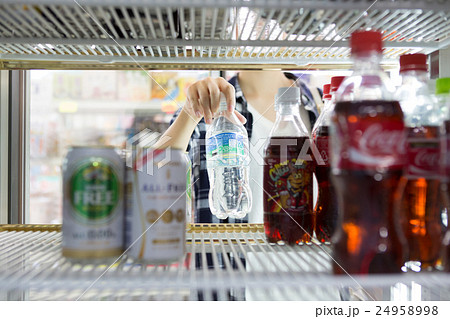 ドリンクコーナーの冷蔵庫からミネラルウォーターを取り出す若い女性客 24958998