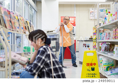 コンビニで座り読みをする女性客と困っている店長 24959011