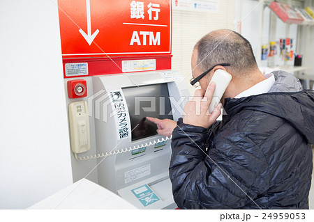 ATMの備え付け受話器で話す中年男性 24959053