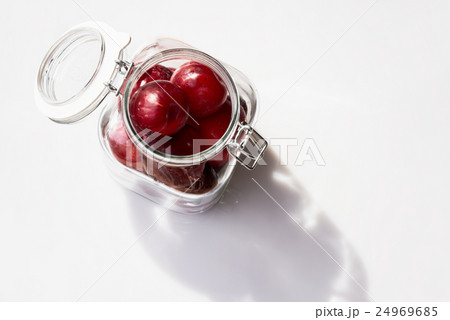 Plums in a glass jar on a white background Plums in a glass jar on a white background 24969685