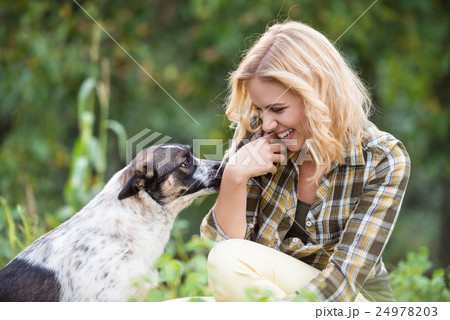 Beautiful blond woman with dog in green garden Beautiful blond woman with dog in green garden 24978203