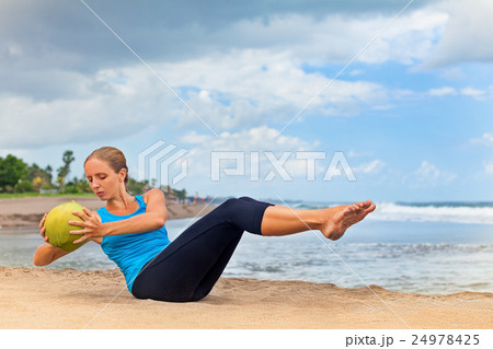 Woman fitness exercise withcoconut on ocean beach 24978425