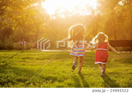 Two sisters running on the lawn 24993522