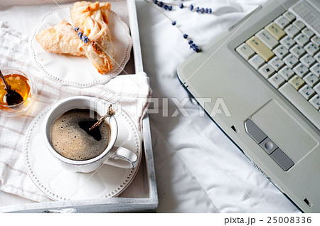 A cup of coffee with the laptop on the bed A cup of coffee with the laptop on the bed 25008336