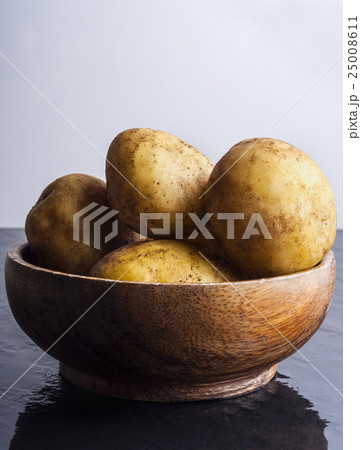 Raw potatoes in bowl on stone table 25008611