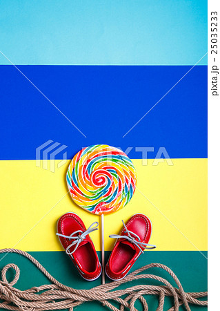 Small red boat shoes near big lollipop 25035233